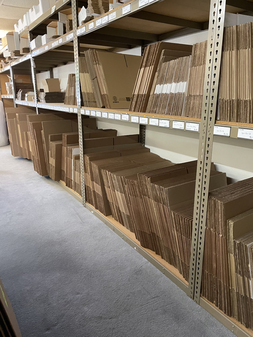 Cardboard boxes of all shapes and sizes shown stacked side-by-side on a shelf ready for sale.