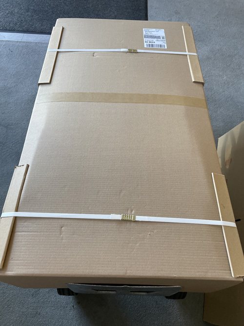 Overhead of a large cardboard box filled with delicate merchandise on a dolly ready for delivery.