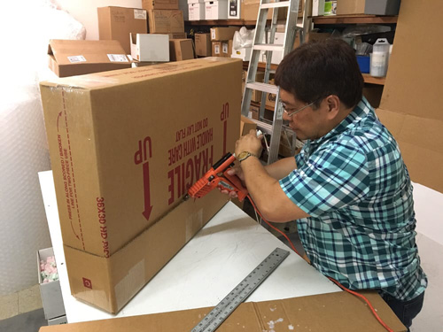 Box World staff using a glue gun to seal a box to ensure the contents remain safe during shipping.